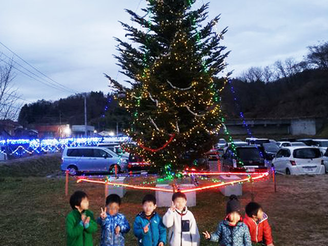 イルミネーションが灯ったクリスマスツリーとポーズを取る子供たち